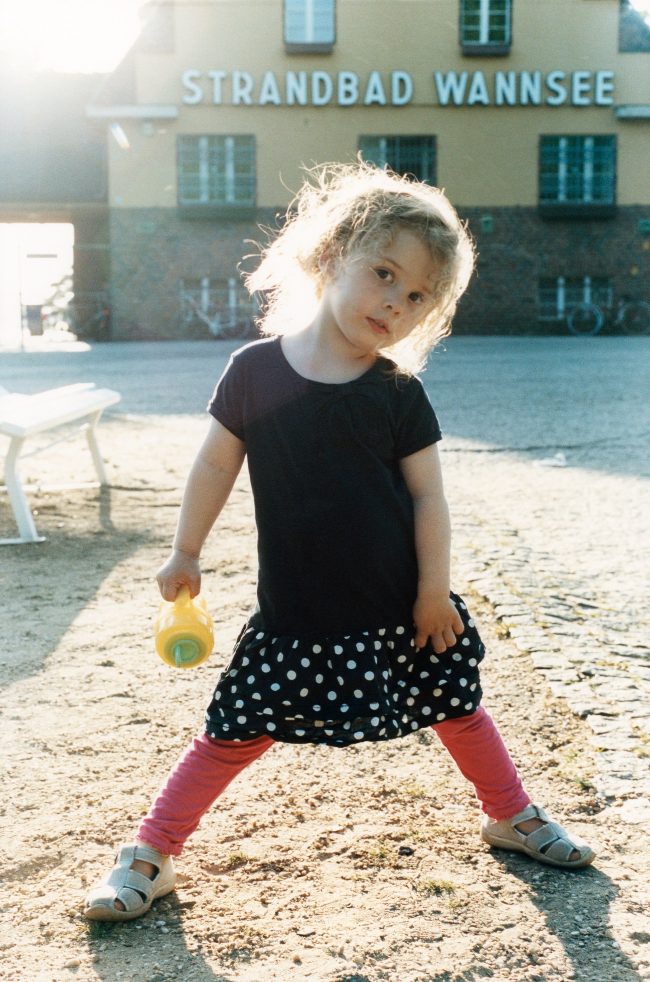 A young child plays on the sandy beach at Strandbad Wannsee with the facility building visible behind.