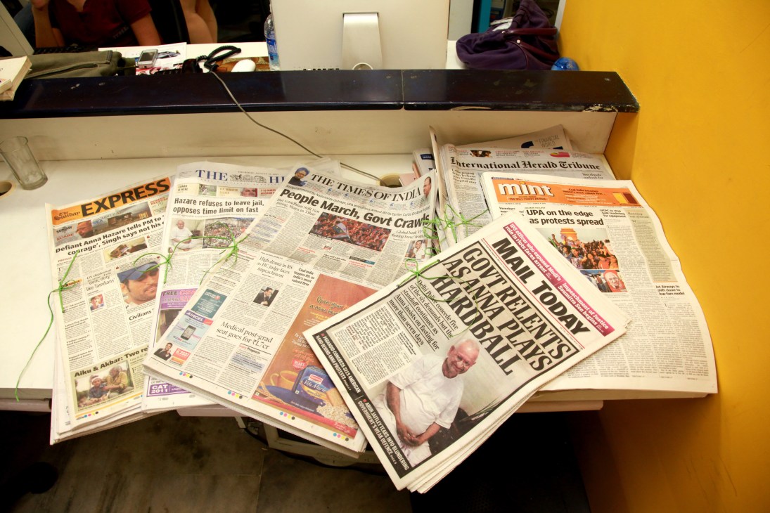 Multiple Indian newspapers spread on a white desk, including The Times of India, Express, and Mint publications.