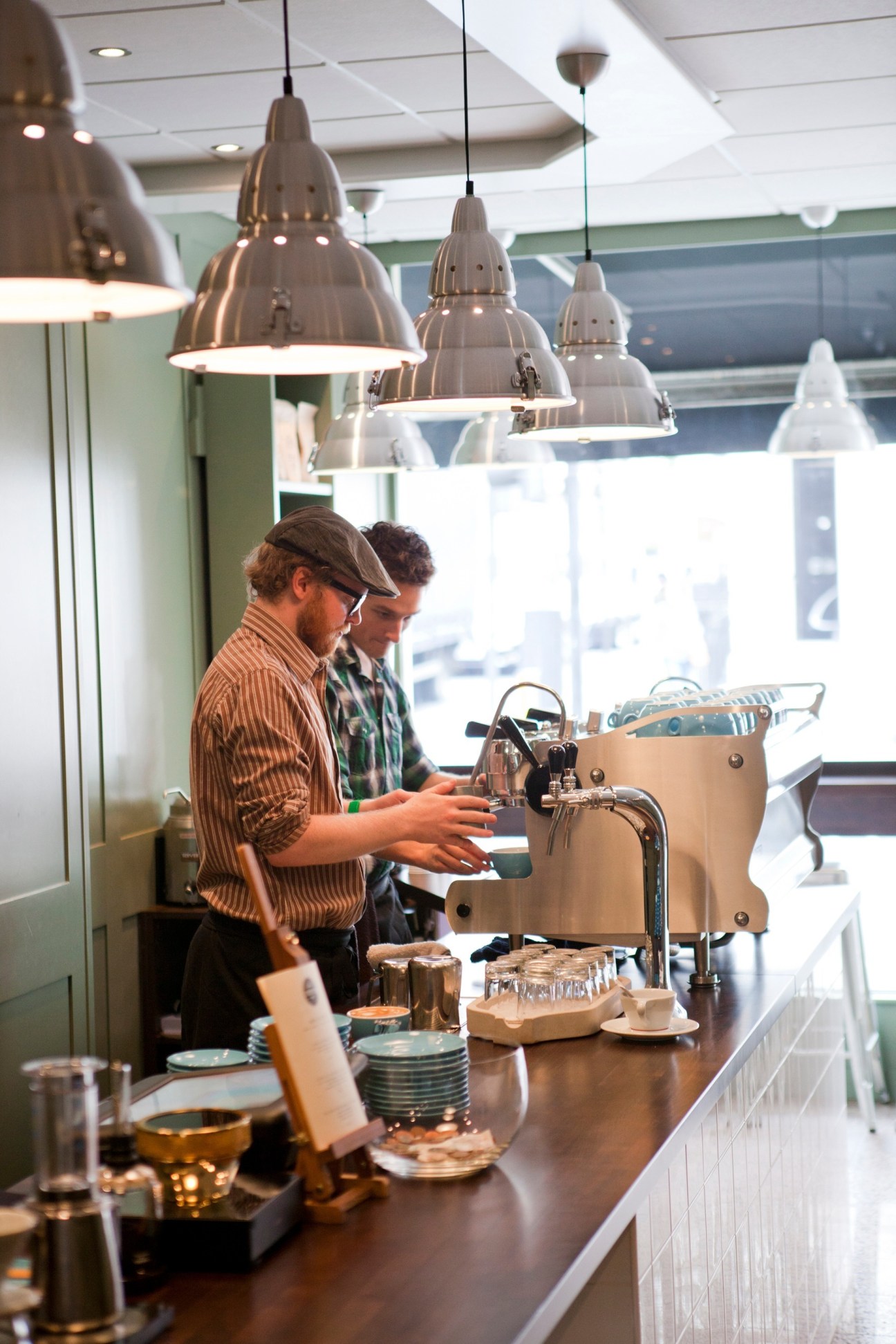 Barista preparing specialty coffee at Sensory Lab in London, with industrial pendant lights overhead.