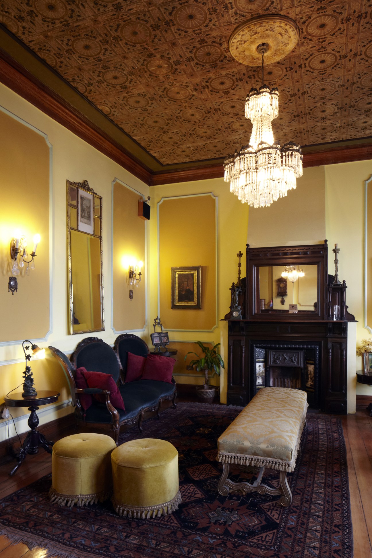 Ornate Victorian interior with yellow walls, chandelier, fireplace and period furniture at Gran Hotel Gervasoni.
