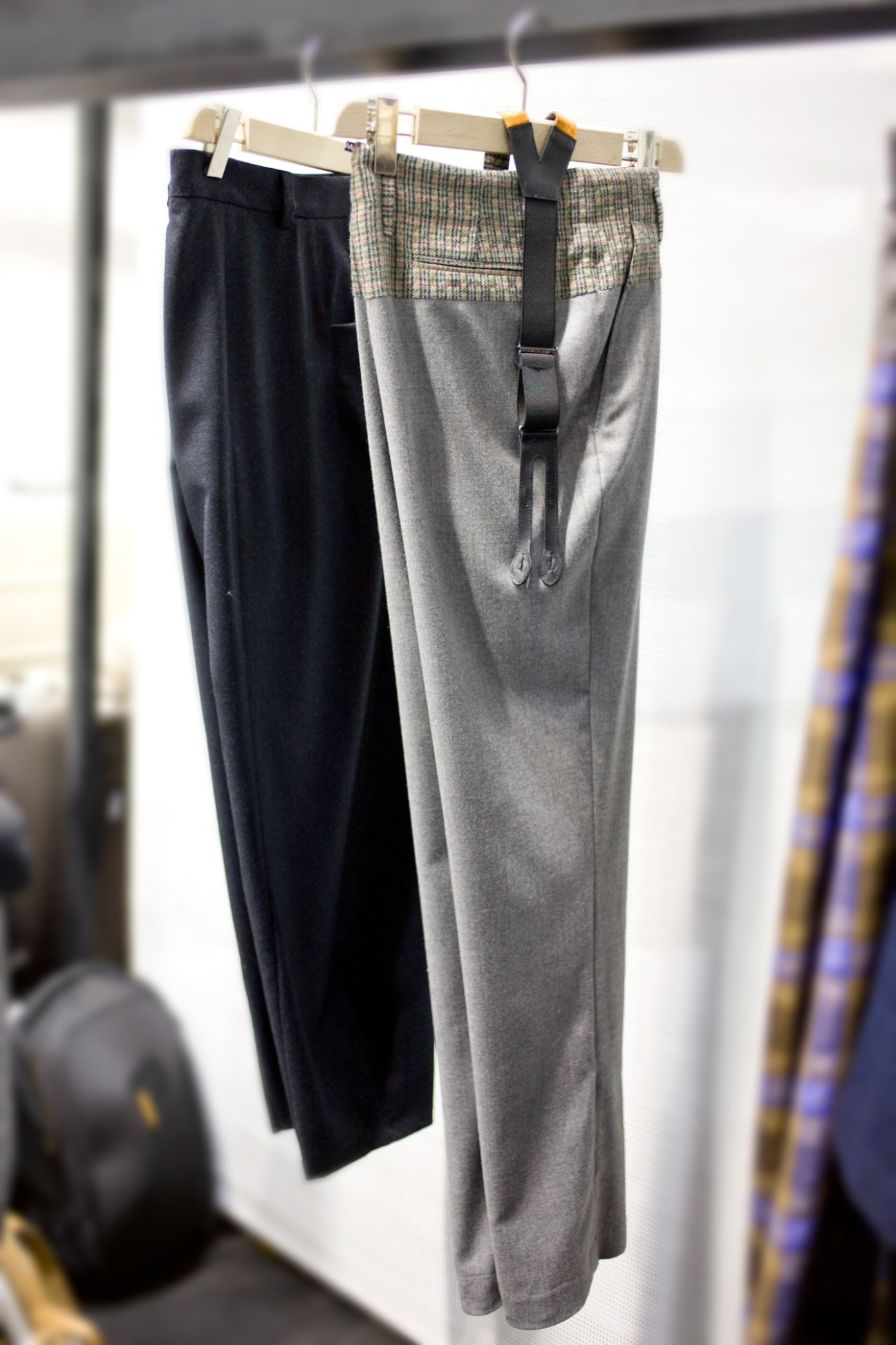 10A trousers displayed on hangers, featuring navy and grey wool styles with patterned waistbands.
