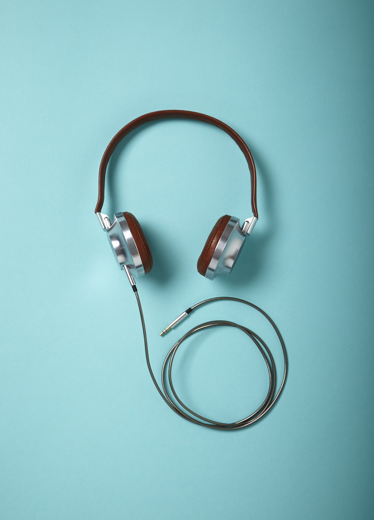 Aëdle VK-1 headphones with lambskin ear pads and attached cable on light blue background.