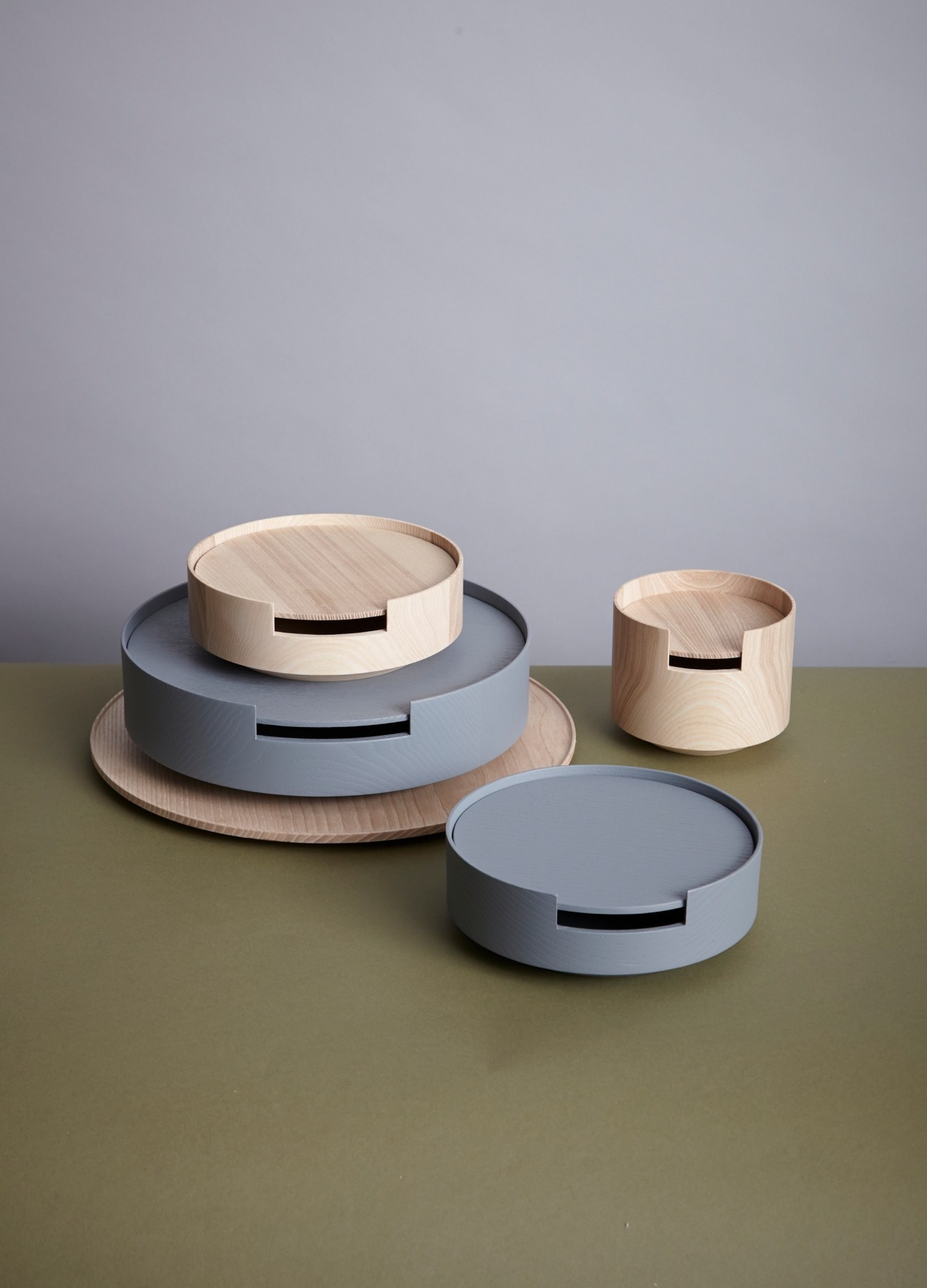 Three minimalist wooden containers in various sizes with ash and grey finishes, featuring slot details on lids.
