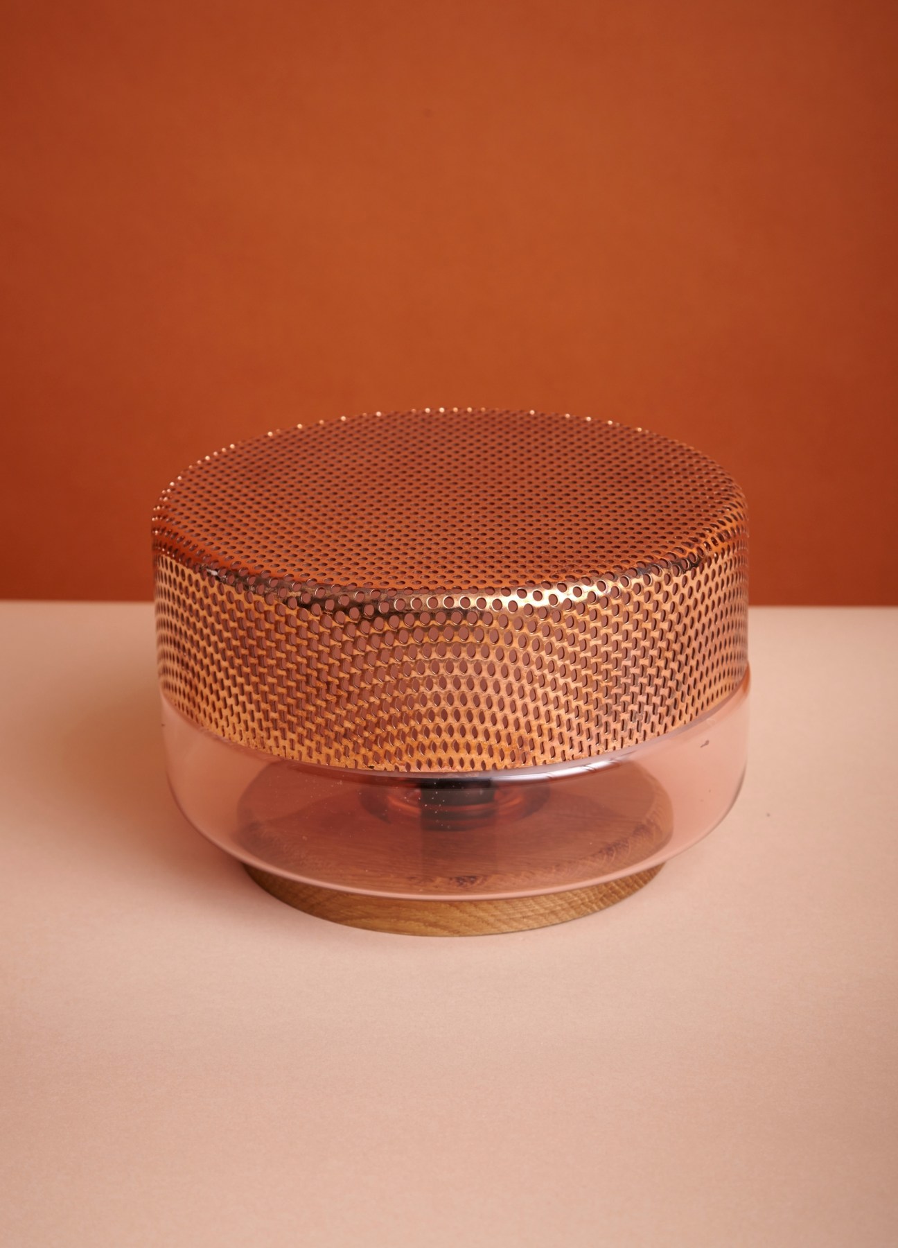 Pulpo table lamp with blown glass base and perforated steel shade on pink surface