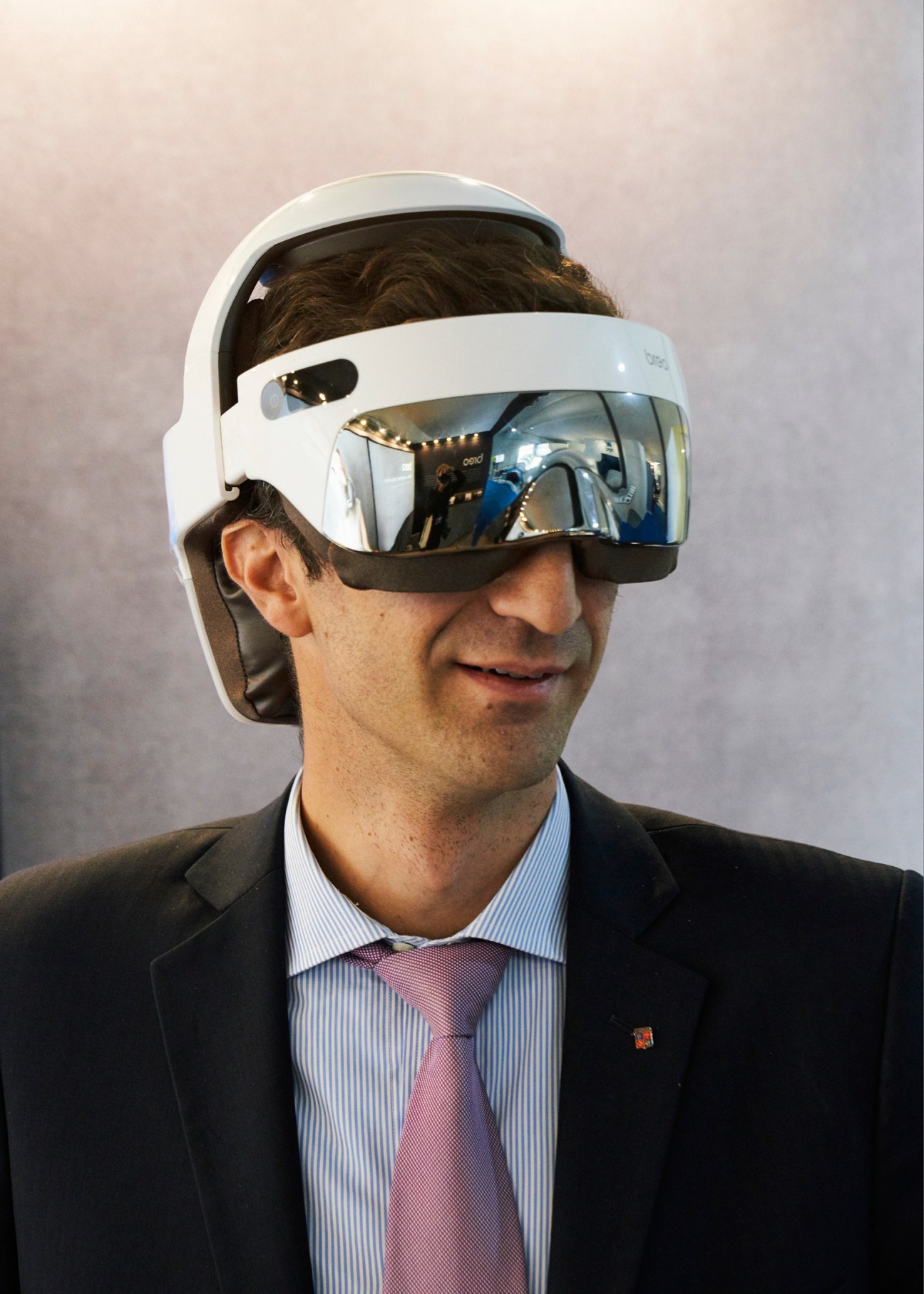 Man in business suit wearing white VR headset with reflective visor, demonstrating virtual reality technology