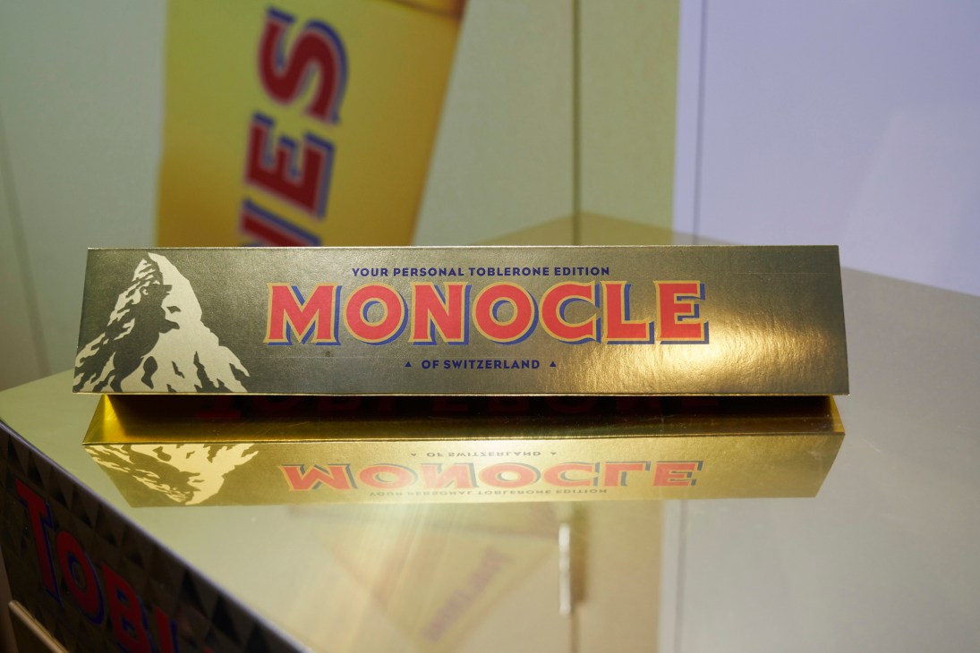 Golden Toblerone chocolate bar with personalized 'MONOCLE' branding and Swiss mountain imagery on display shelf