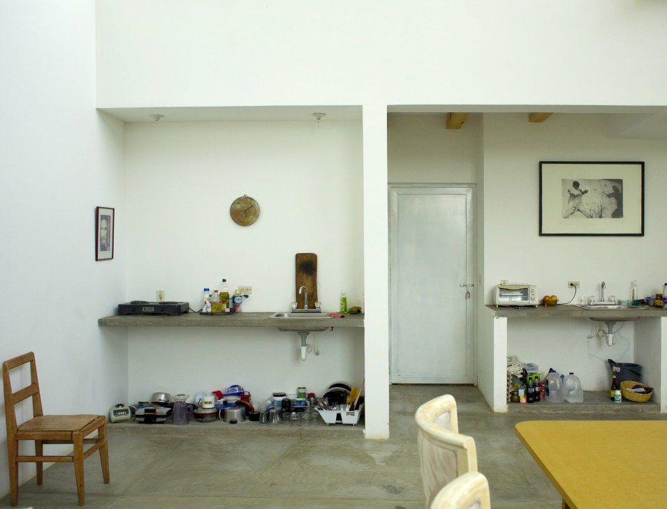 Artist Christina Chow's minimalist studio interior with white walls, shelving, and simple furnishings.
