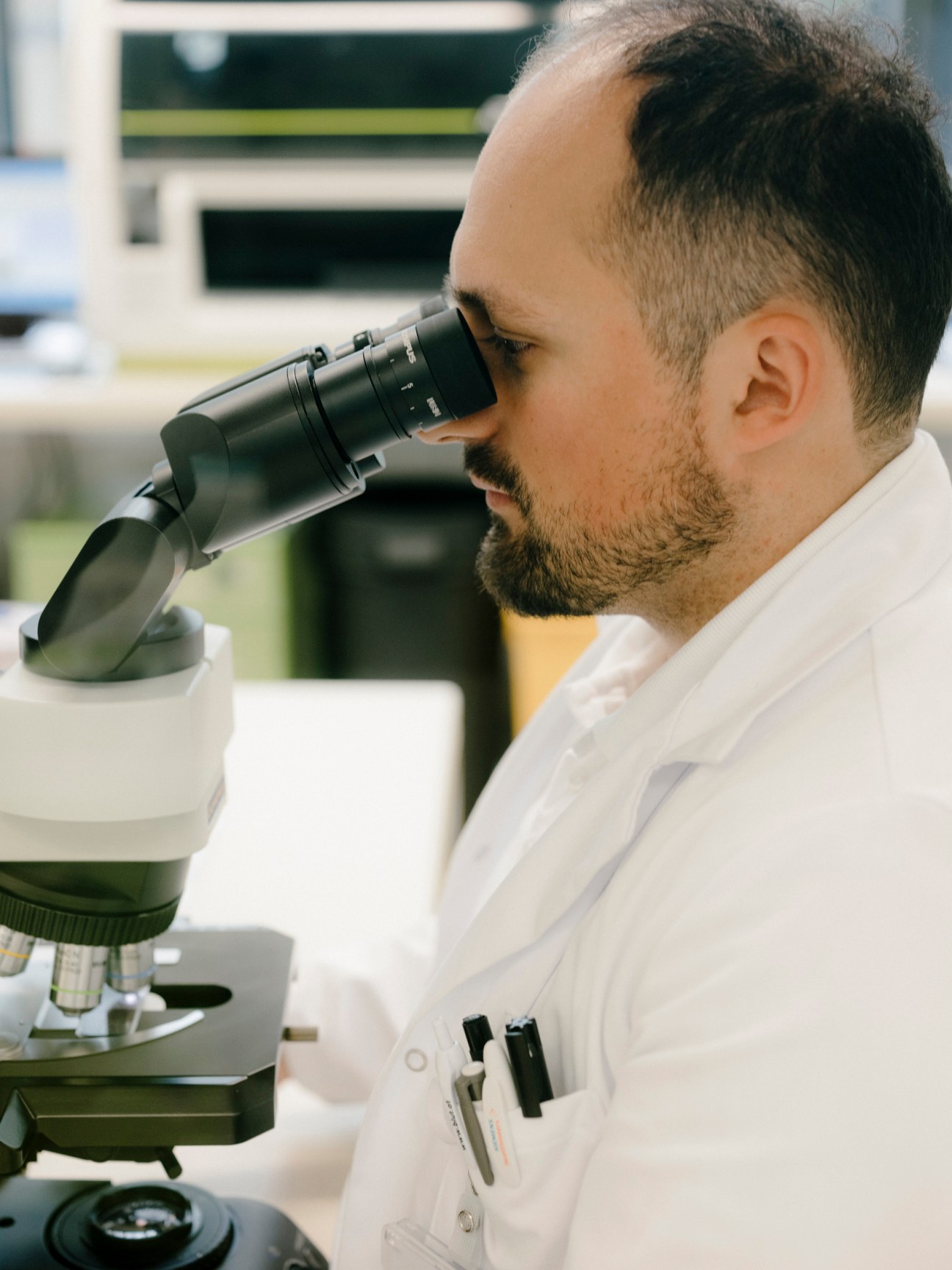 A researcher using a microscope in a modern laboratory at Klinik Floridsdorf hospital.