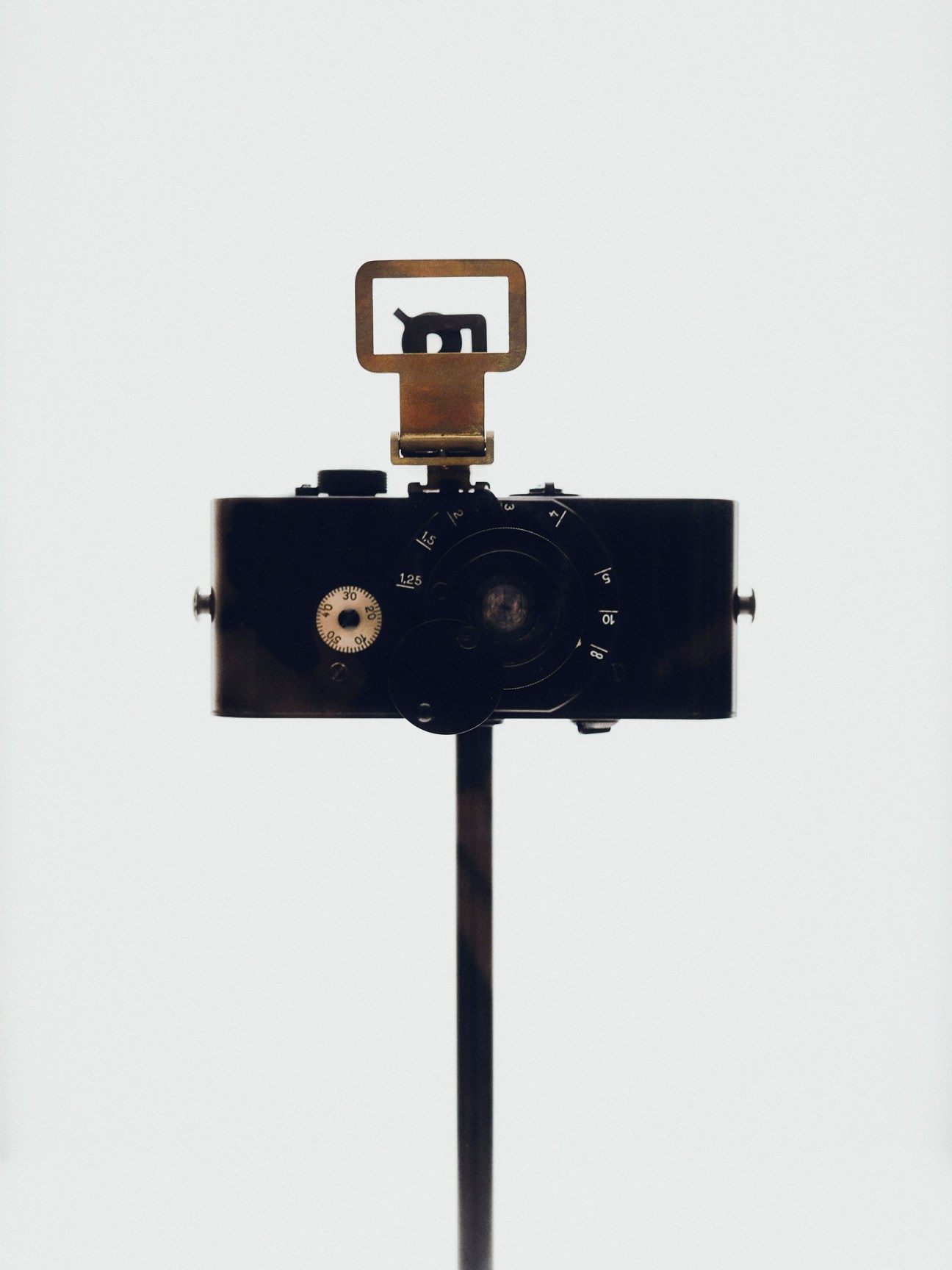 A replica of the Ur-Leica, the first camera developed by Oskar Barnack, displayed on a stand against a white background.