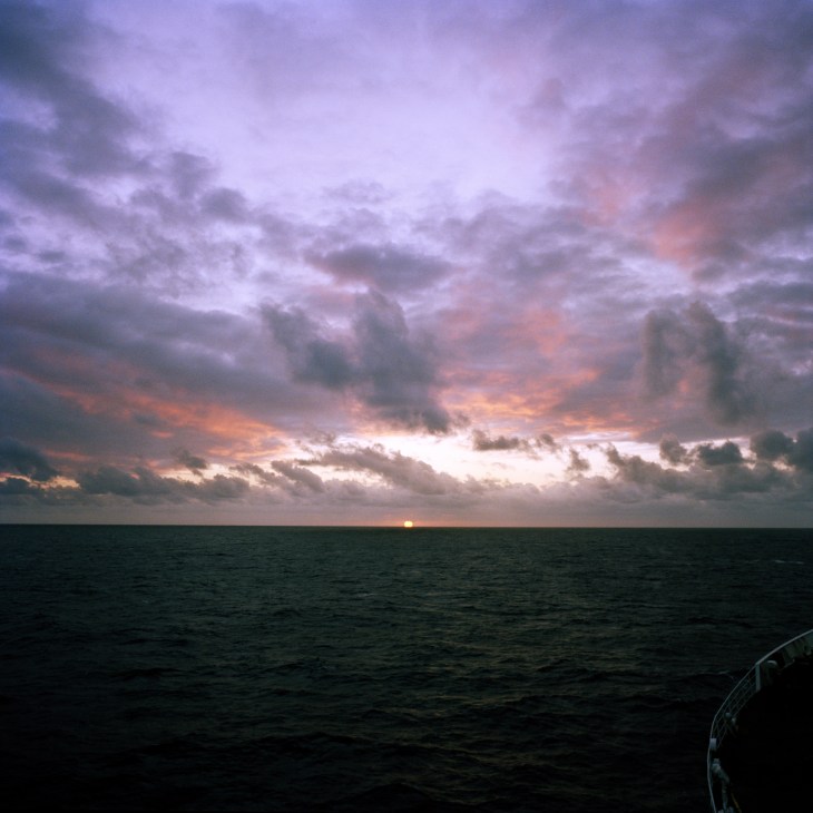Sunset over the South Atlantic Ocean with dramatic clouds lit in orange and pink hues.