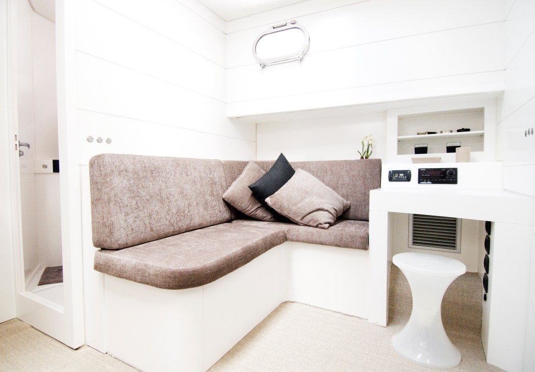 Bluegame 60' interior with taupe upholstered seating, white walls, and compact cabin amenities.