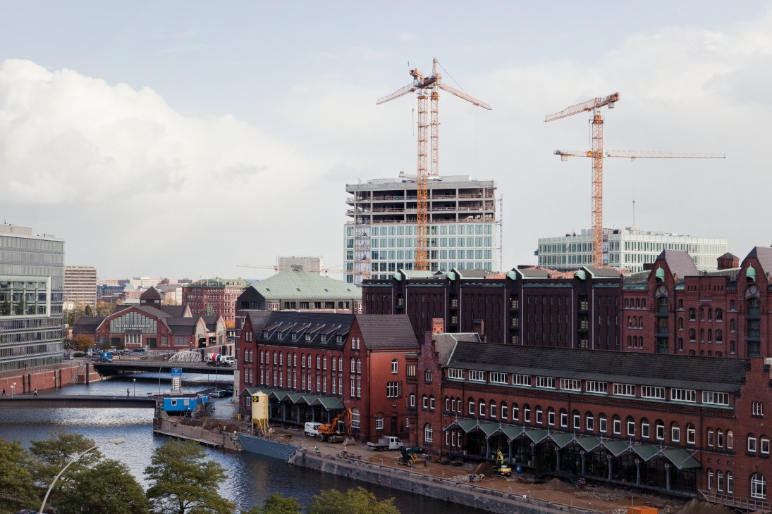Construction cranes rise above new buildings under development in Hamburg's HafenCity waterfront district.