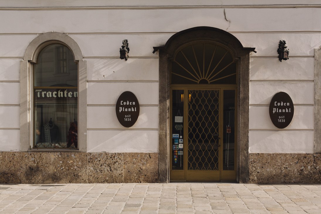 Storefront of Loden Plankl, a traditional Austrian clothing shop established in 1830, with classical architecture and display windows.