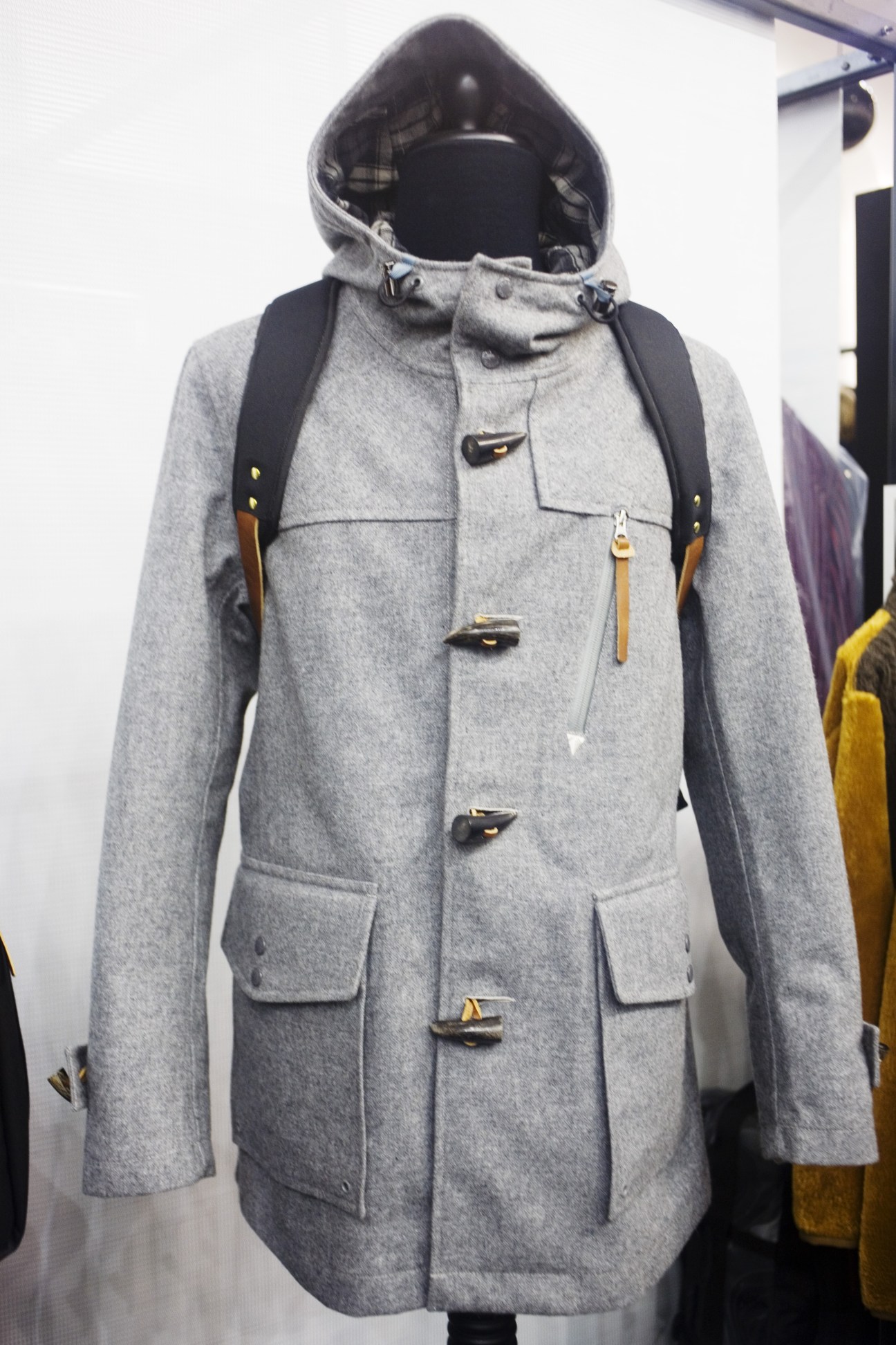 Gray wool duffle coat with hood and toggle buttons displayed on a mannequin.