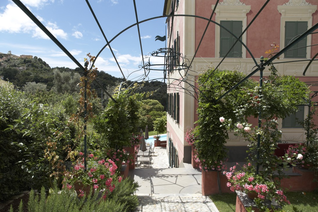 Garden terrace at Villa Rosmarino with flowering plants, pergola and mountain views.