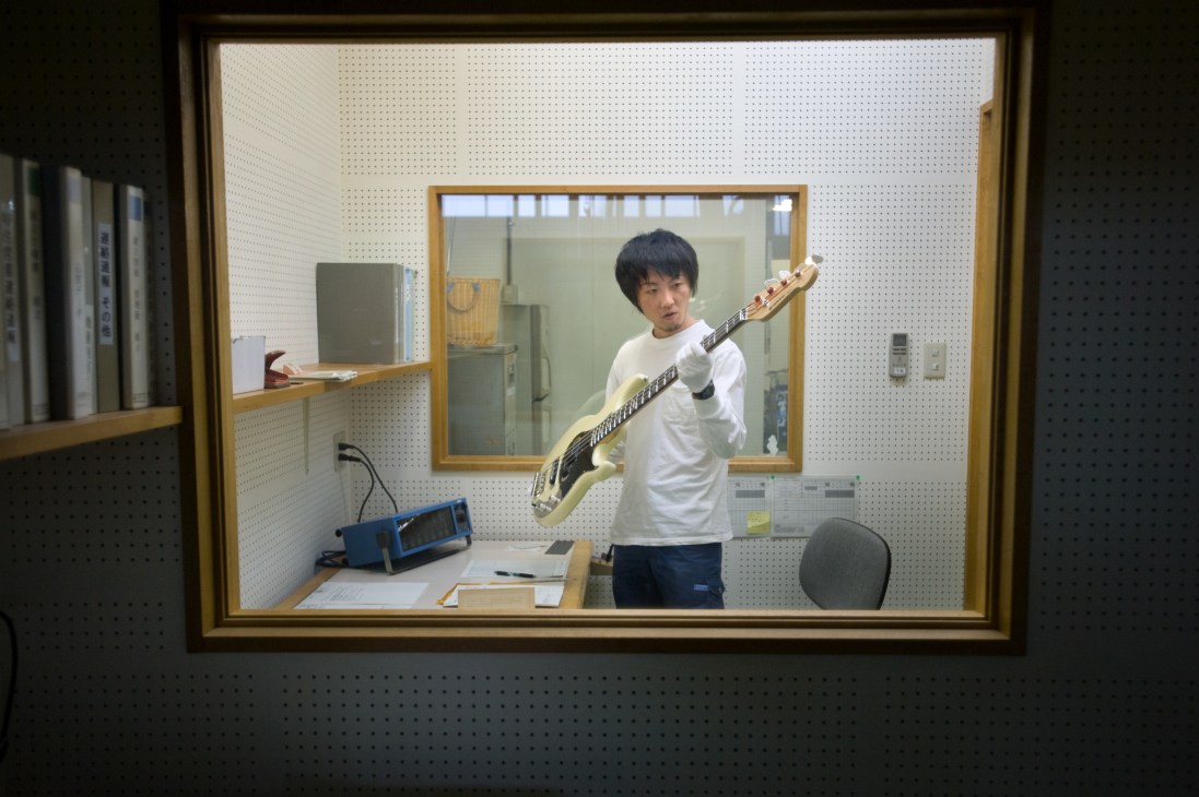 Yutaka Yobayashi tests the sound of a Yamaha acoustic guitar in a soundproof room.