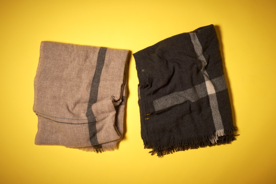 Two folded wool blankets with striped patterns on a yellow background.