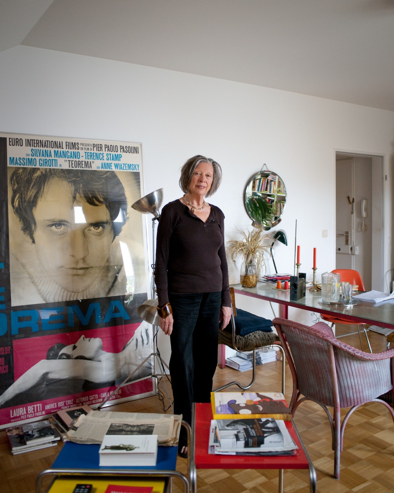 Ulla Rapp stands in her apartment surrounded by film posters and memorabilia displayed as artwork.