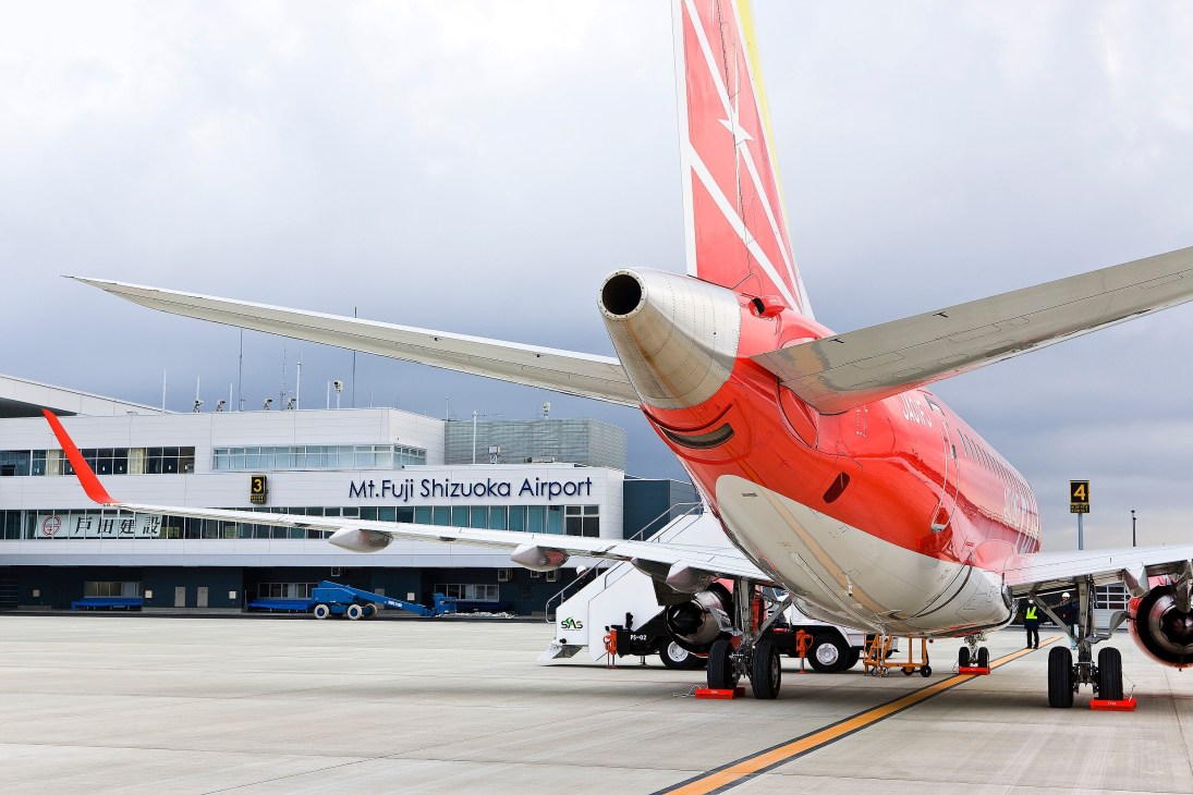 Red Fuji Dream Airlines aircraft parked at Mt. Fuji Shizuoka Airport terminal.