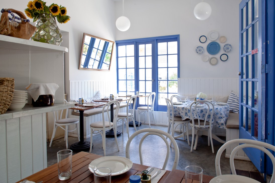 Bright dining room with blue doors, white chairs, and decorative plates on white walls.