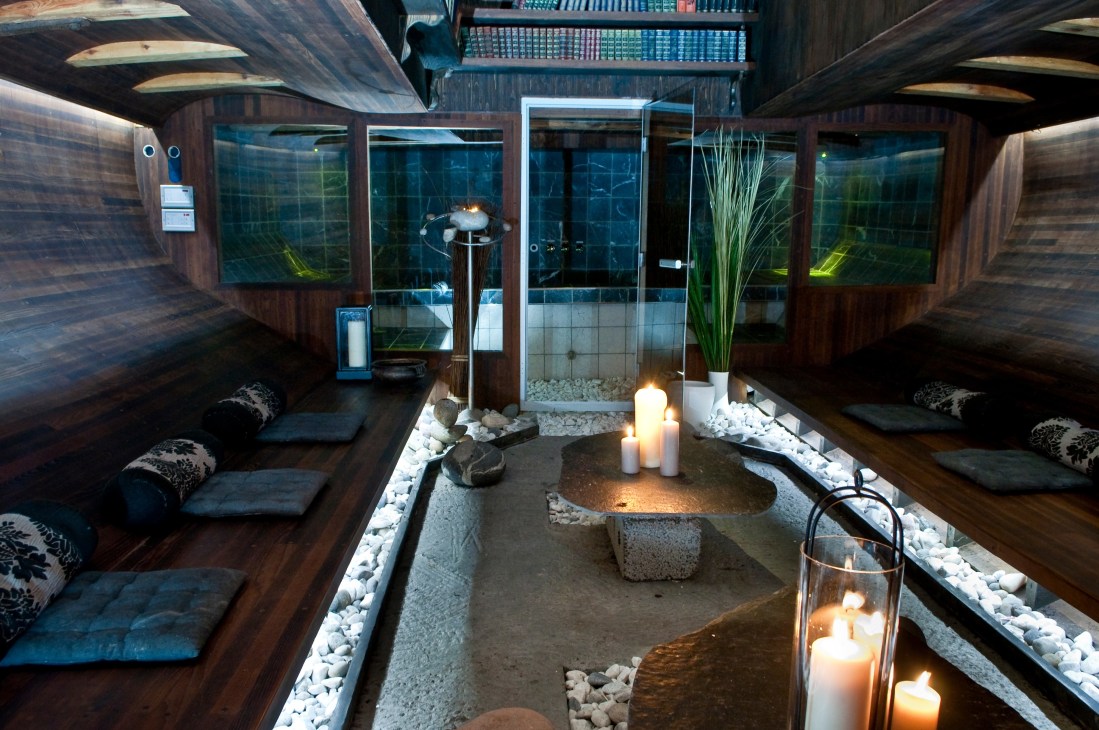 Interior of Vulkana floating vessel showing zen garden with candles, white stones, and modern wood paneling with windows.