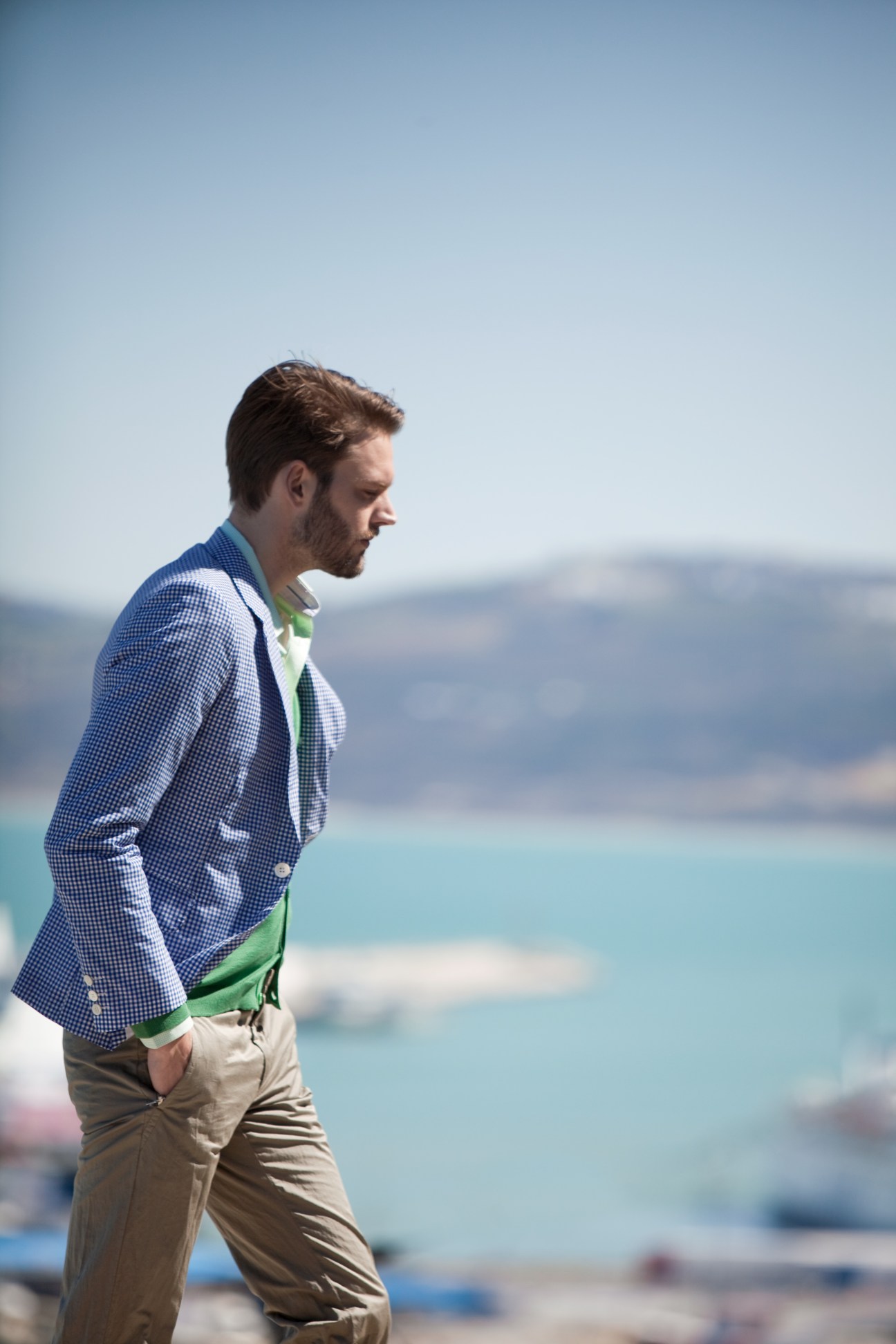 Man wearing blue checked Junya Watanabe jacket and cardigan overlooking Tangier waterfront.