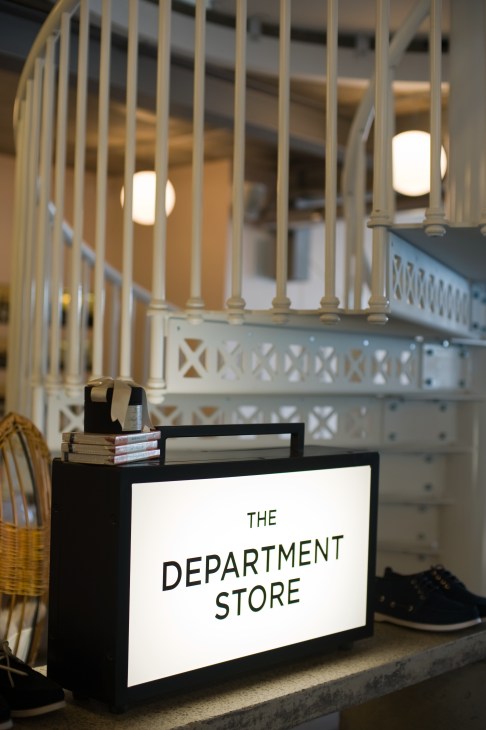 The Department Store reception desk with illuminated signage and white railing staircase.