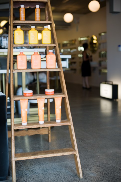 Wooden ladder display with colorful beauty product bottles in orange, yellow, and peach tones in The Department Store.