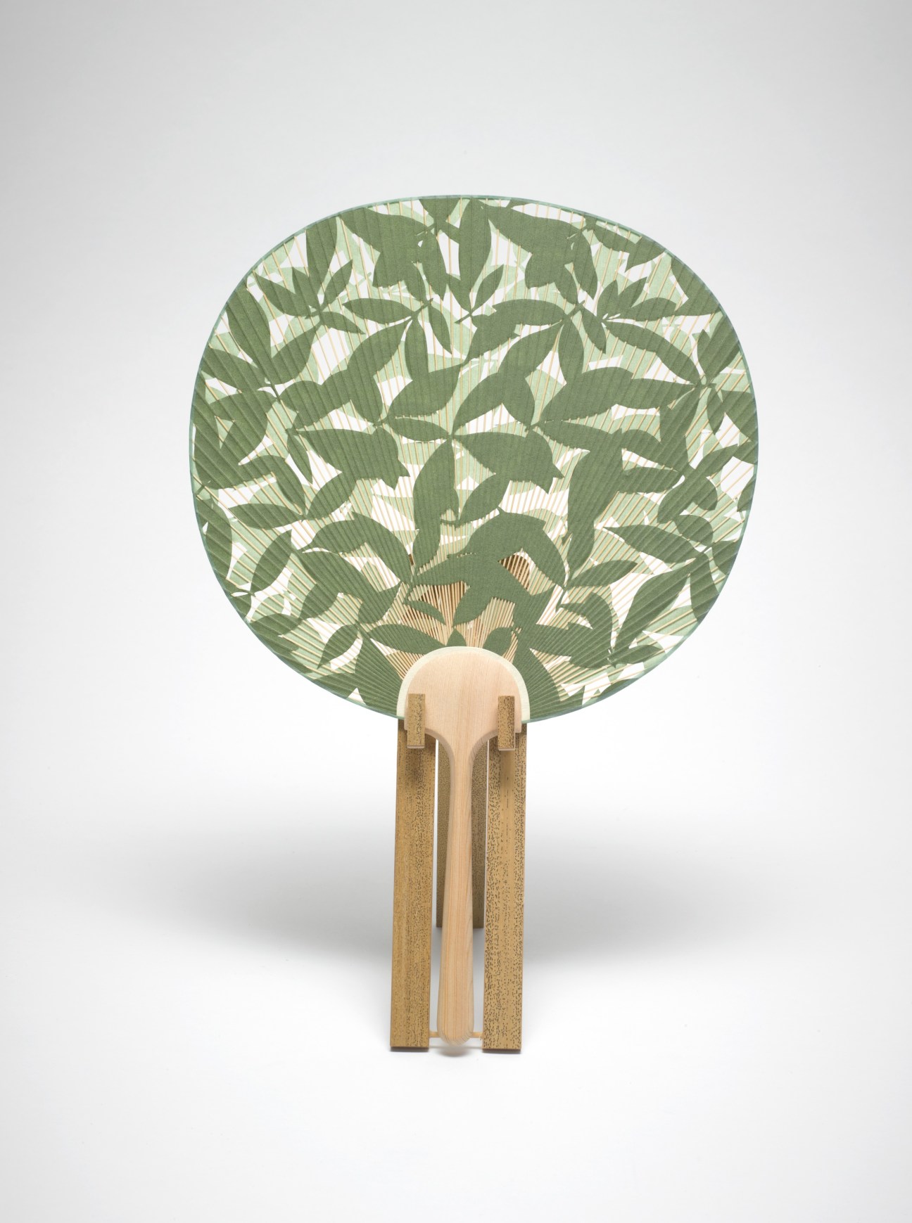 Handmade Aiba uchiwa fan with green bamboo leaf pattern on circular paper and wooden handle.