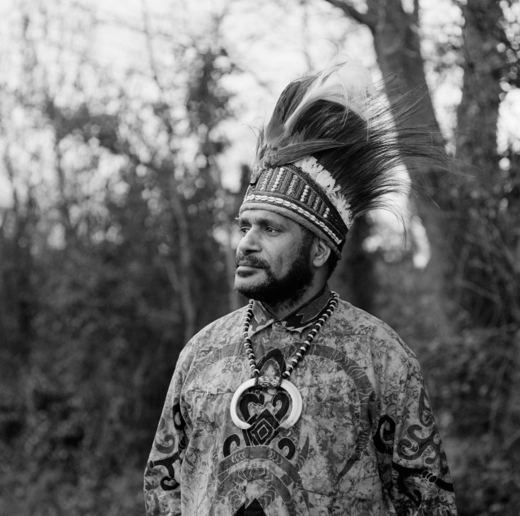 Benny Wenda, West Papuan independence leader, wearing traditional tribal headdress and ornamental necklace in a forest setting.