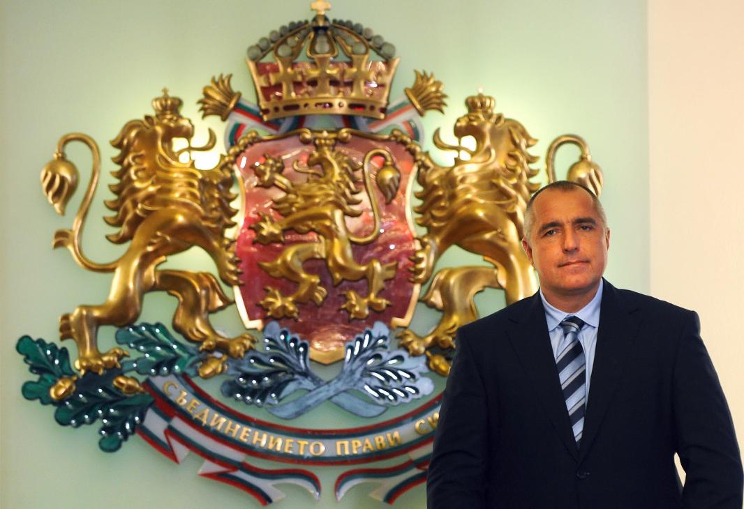 Boyko Borisov, Bulgarian Prime Minister, stands in front of the Bulgarian national coat of arms.