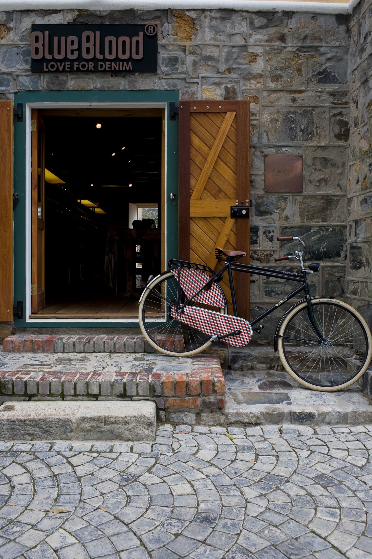 Blue Blood Denim storefront with exposed stone facade, bicycle parked outside entrance.