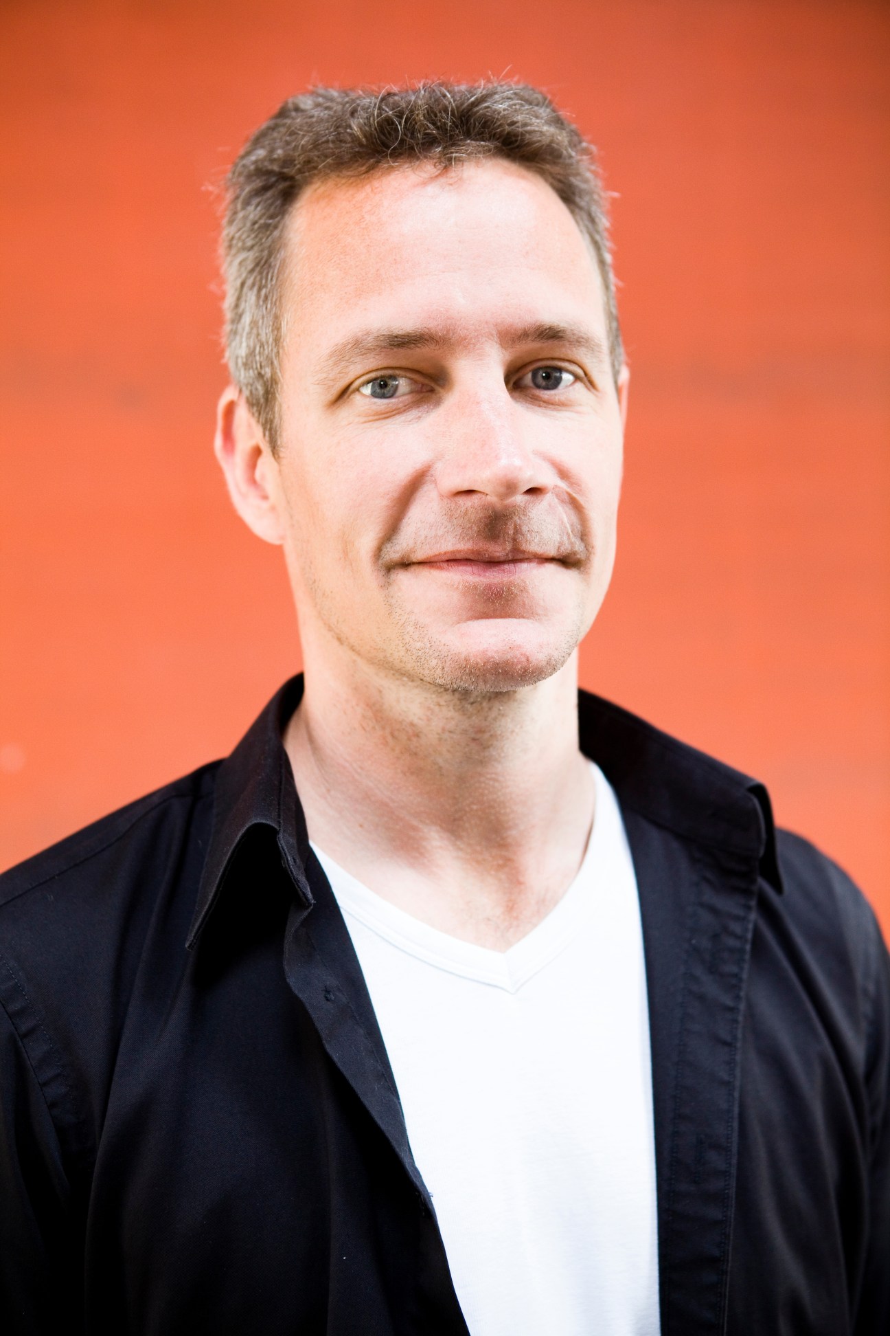 Portrait of Richard Sparrenhök, production and purchasing manager at Iris Hantverk, against an orange background.