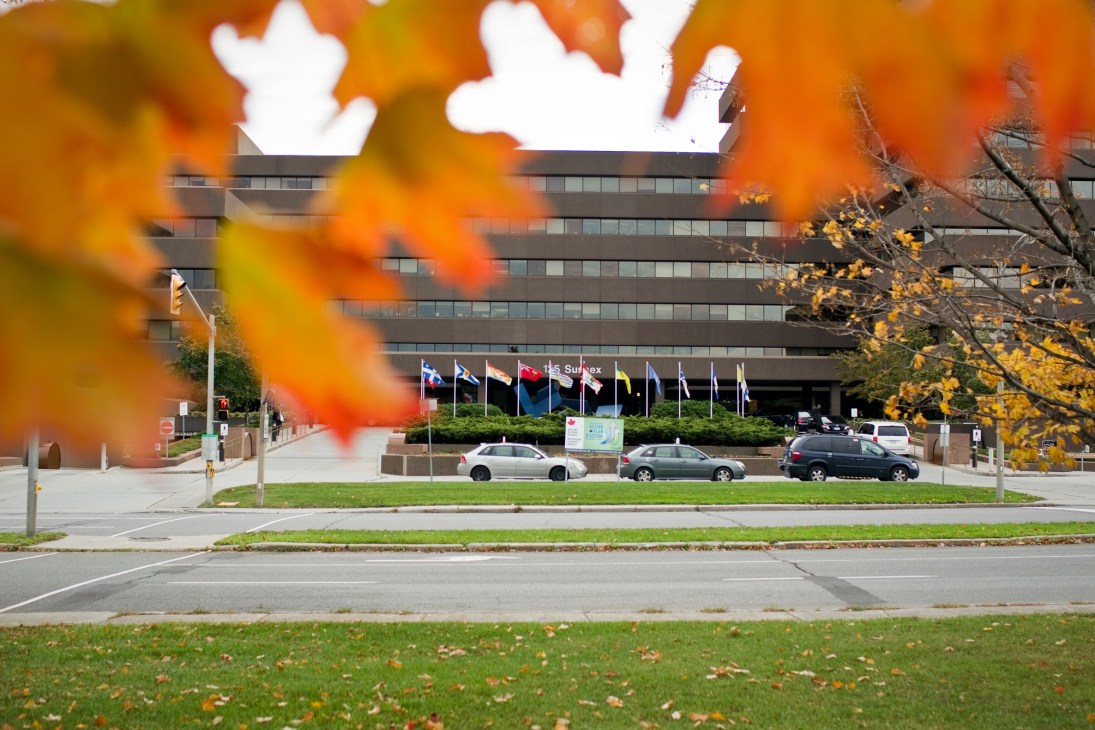 The Lester B Pearson Building in Ottawa with international flags in front, autumn foliage in foreground.