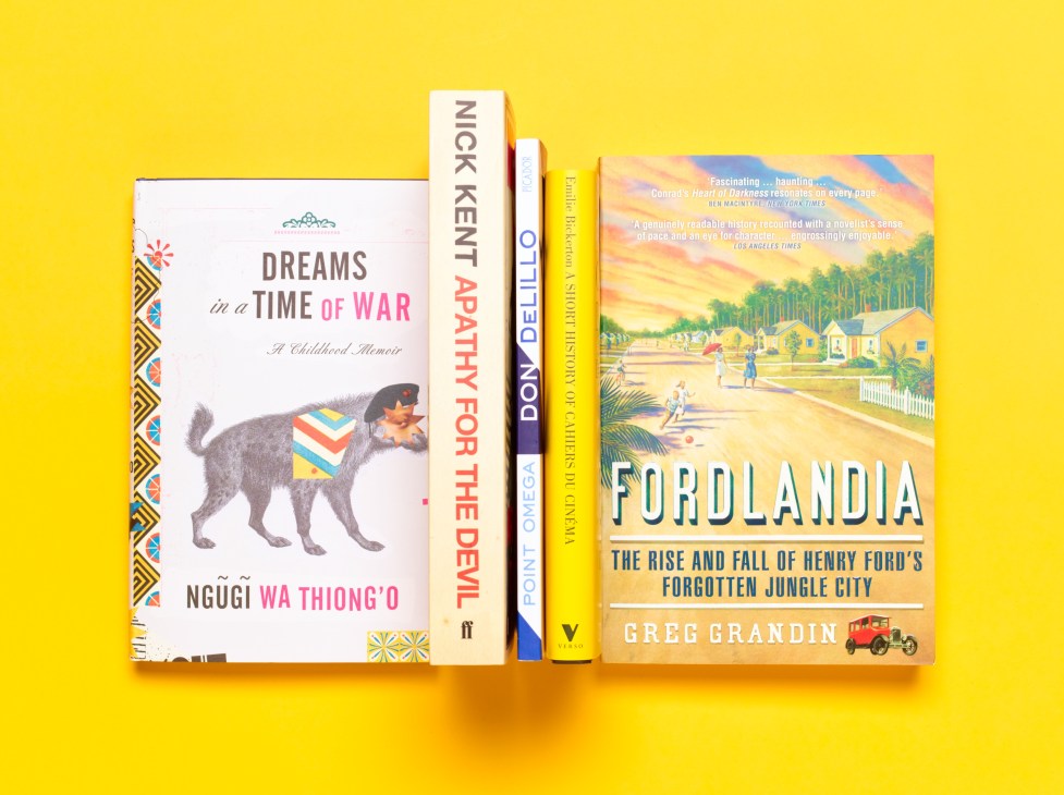 Five books displayed on a bright yellow background including Dreams in a Time of War by Ngugi Wa Thiong'o, Nick Kent Apathy for the Devil, Point Omega, and Fordlandia by Greg Grandin.