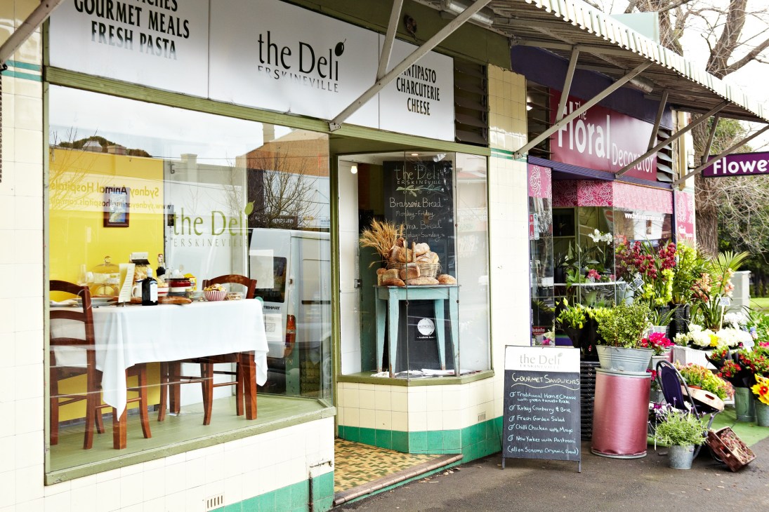The Deli and The Floral Decorator storefronts on Erskineville Road with green trim and shop windows displaying flowers and food items.