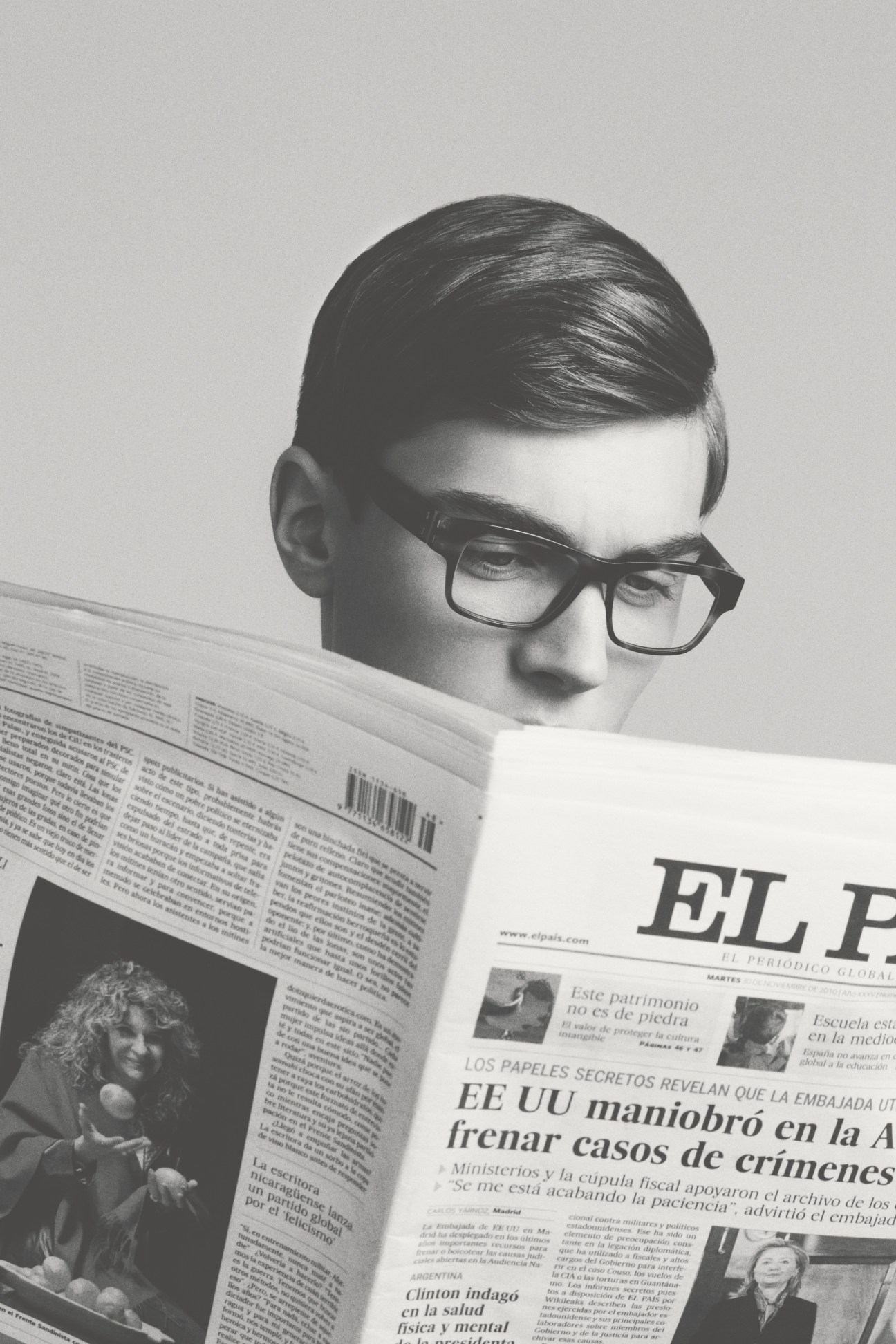 Man wearing Mykita Monika glasses reading a newspaper in black and white portrait.