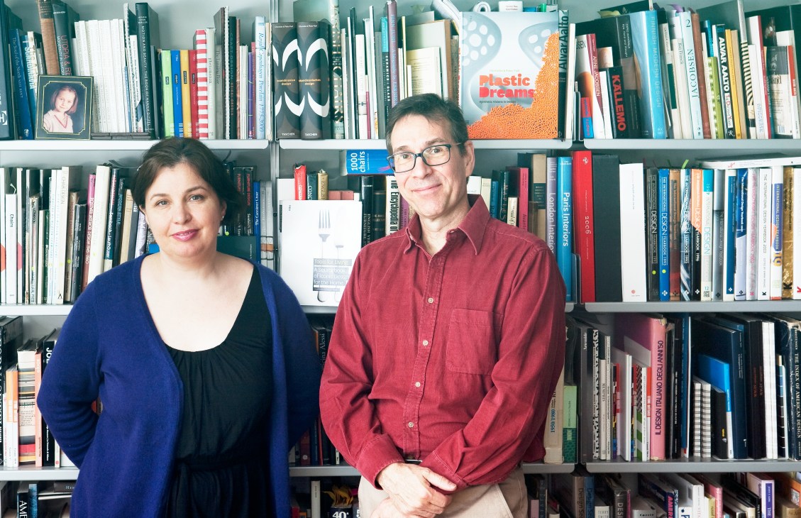 Charlotte and Peter Fiell stand in front of bookshelves filled with design books and publications.