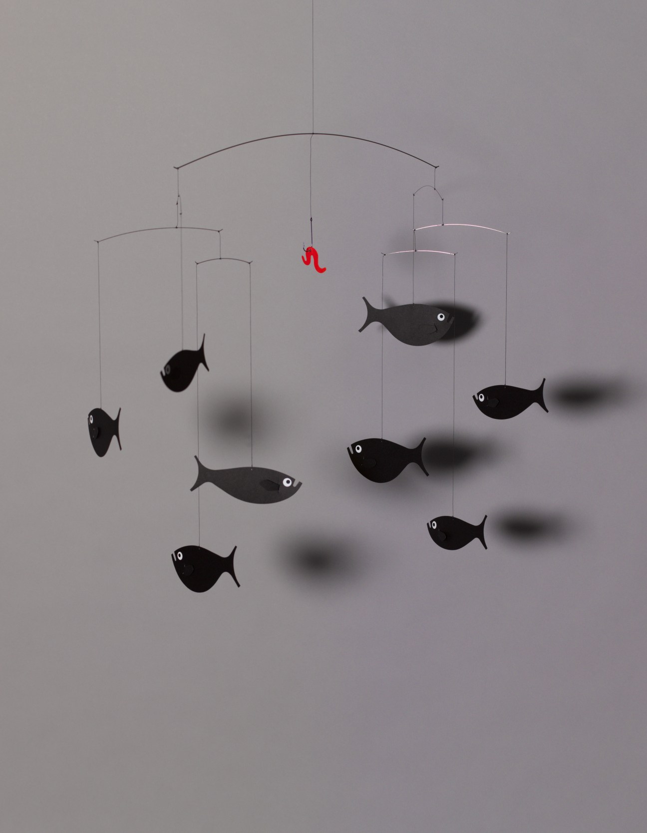 Flensted Mobiles' Shoal of Fish mobile with black fish and a red worm suspended from wire arms.