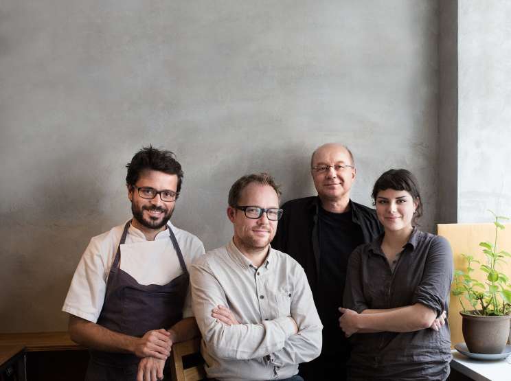 Four food experts standing against a white wall: Christian Puglisi, Søren Ejlerson, Tor Nørretranders, and a fourth panelist.