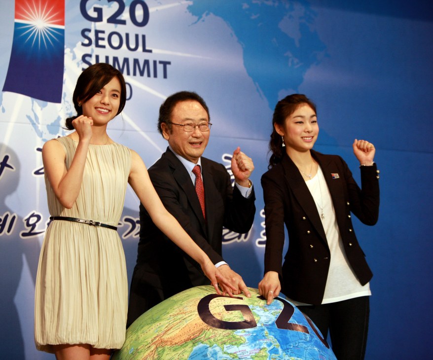 Three people pose with a large globe at the G20 Seoul Summit backdrop.