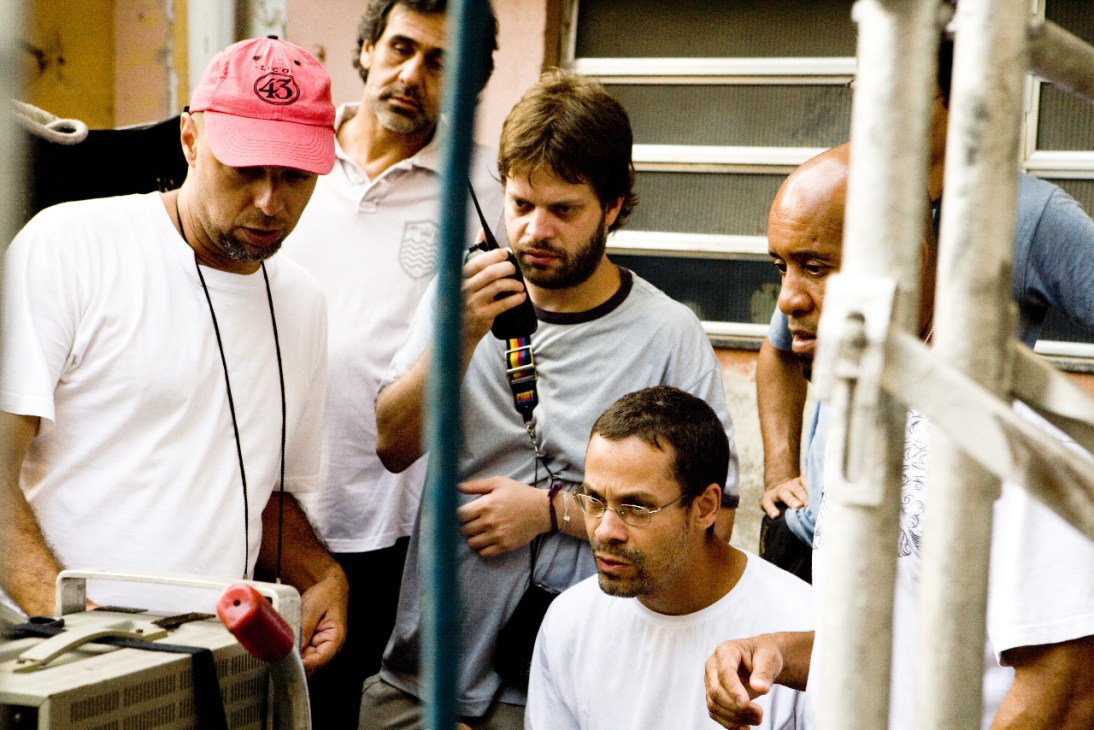 José Padilha and crew members on set during filming, with one wearing a pink cap.