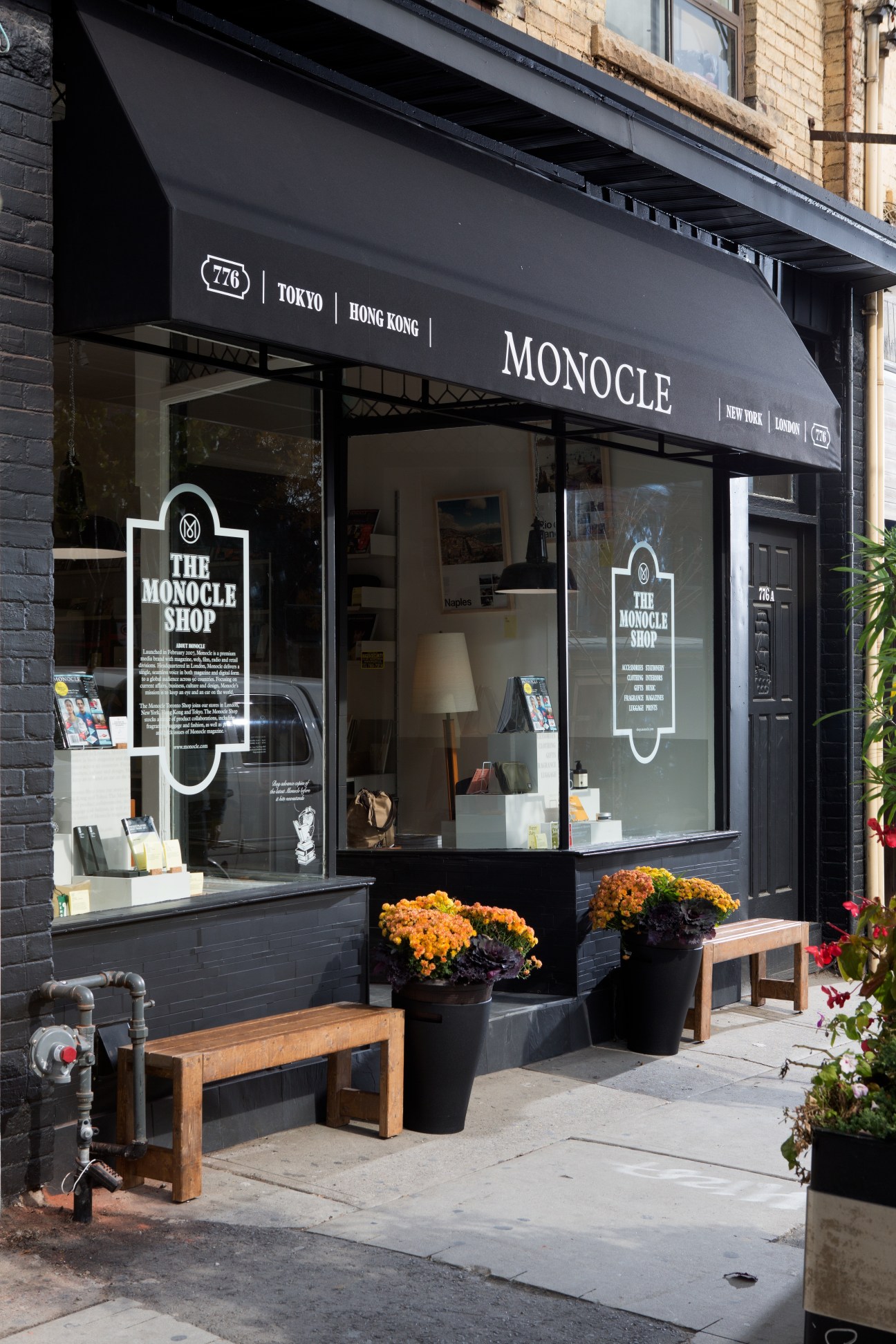 The Monocle Shop storefront on Toronto's College Street with black awning, large windows, and potted flowers.