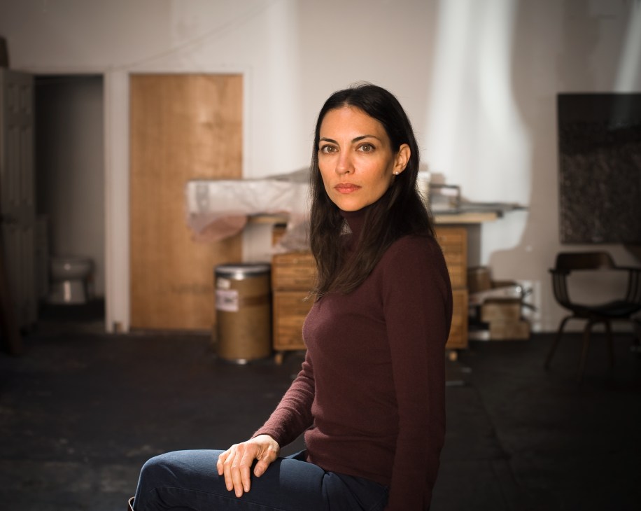Artist Teresita Fernández sits in her Brooklyn studio surrounded by wooden panels and graphite materials.