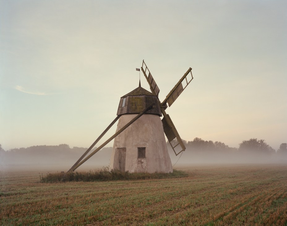 A traditional windmill stands in a misty Gotland field at dawn.