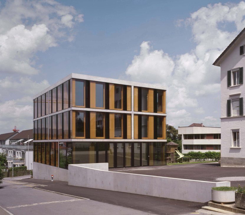 Modern primary school building with gold and black striped facade and large windows in Zurich.