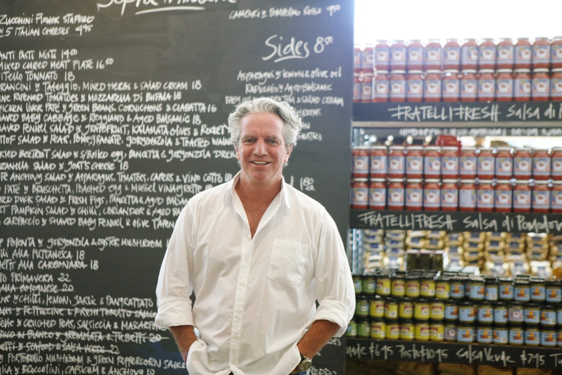 Barry McDonald stands in front of a menu board and shelves of Fratelli Fresh products at his store.