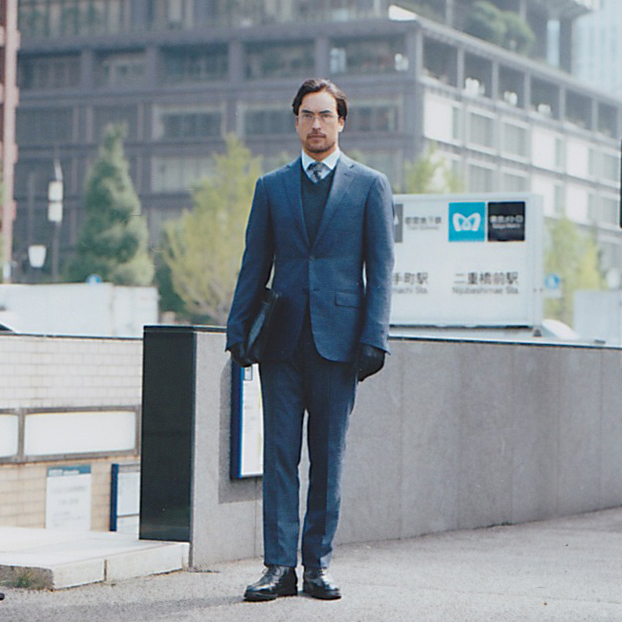 Man in blue Ermenegildo Zegna suit with Boss Black jumper standing outdoors.