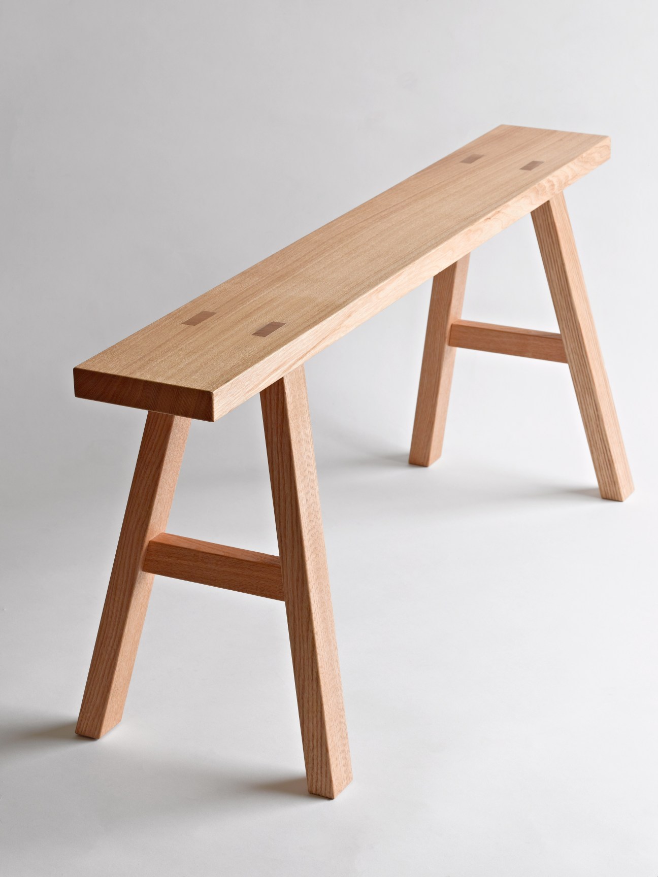 Natural oak bench with simple A-frame wooden legs and crossbar from Muji's Found collection.