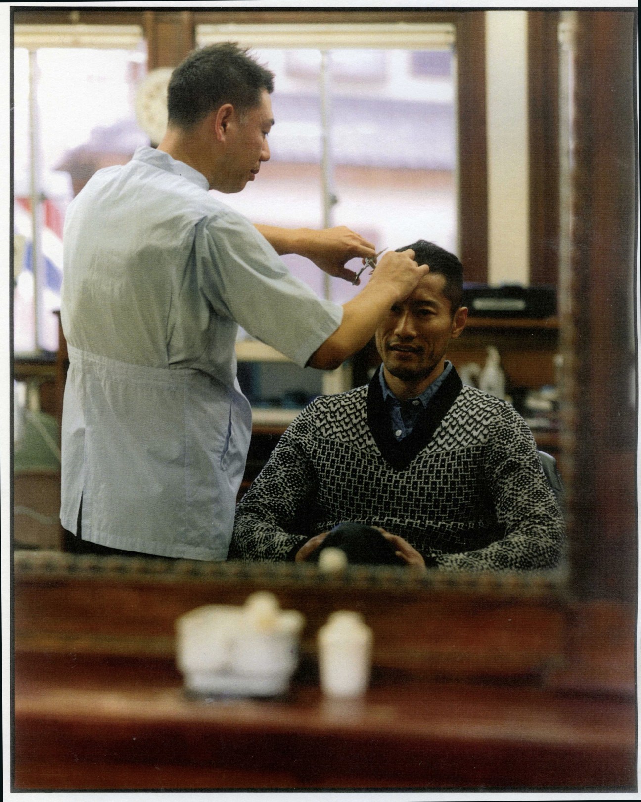 A barber cuts a customer's hair at Totaken, a traditional Tokyo barber shop.